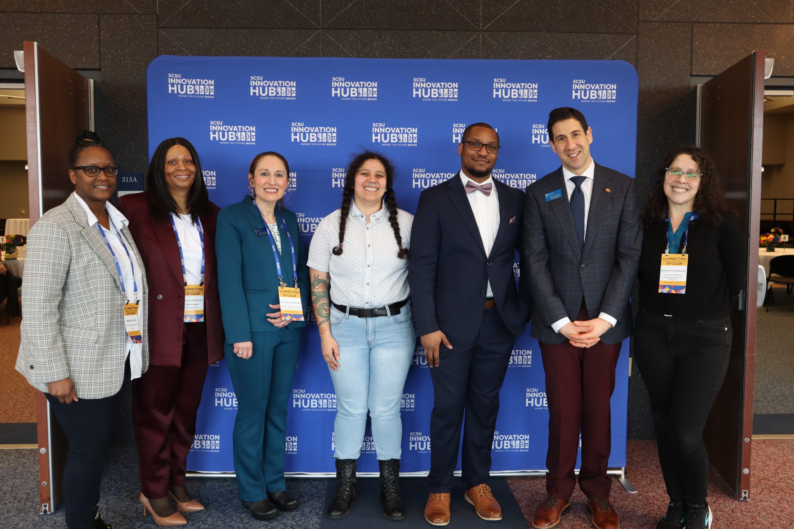 event panelists and staff smiling in front of the event banner
